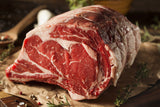 Large chunk of Lynch Farms raw prime rib meat surrounded by fresh herbs and spices